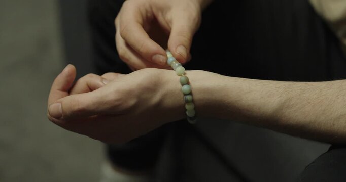 Close-up of hands playing with a bracelet. Concept of nervous habit, fidgeting and casual hand movement.