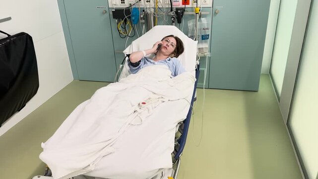 Female patient lying in a hospital bed using a smartphone. Concept of healthcare, recovery, communication and modern patient lifestyle.