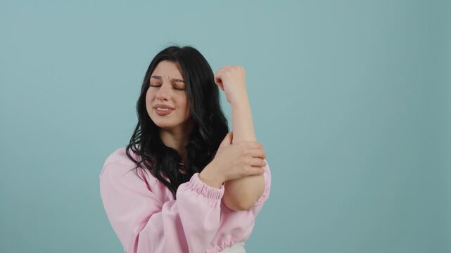 Young woman suffering from elbow joint pain and touching arm