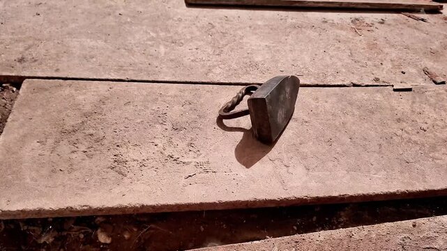 Heavy cast iron flat iron with curved handle resting on dusty stone slabs, rustic textures highlighting historic household tool from an earlier era of clothing care