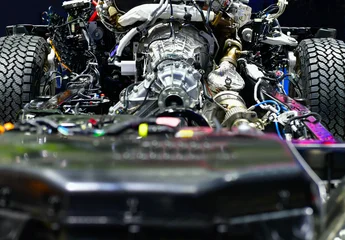 Detailed view of an internal combustion engine and 4x4 drivetrain mounted on a vehicle frame, showing mechanical components. © I Viewfinder