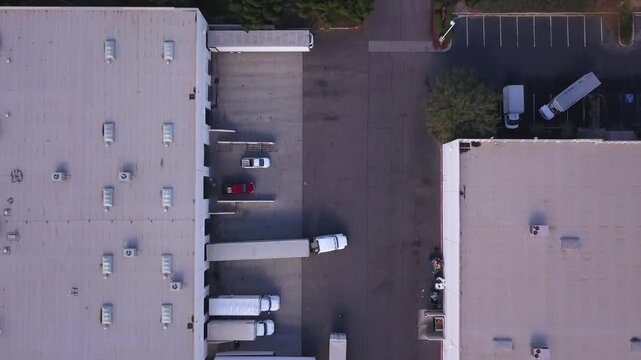 Top-down drone view of an industrial warehouse in Calexico, California, showing loading docks, trucks, and parking areas