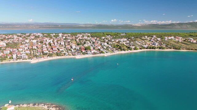 Drone facing Pako&scaron;tane from the Adriatic, showing both the sea and Vrana Lake behind the town. As the drone turns along the coast, the full length of the village and lake is revealed.