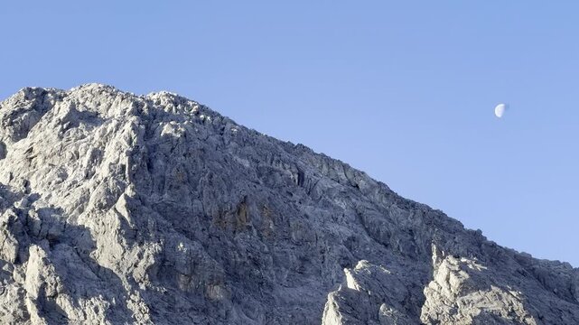 Mountain glowing during golden hour at sunrise with moon next to it - taken from the entrance of Samaria Gorge National Park, Crete