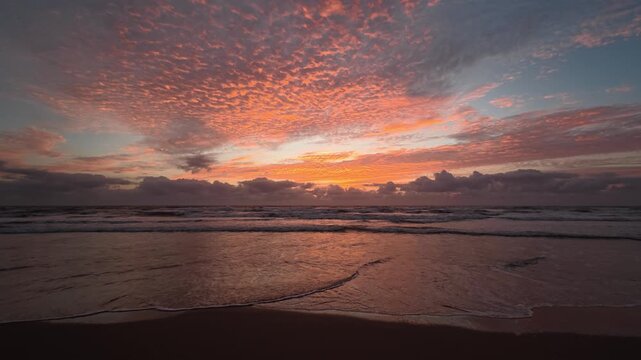 The breathtaking beauty of a coastal dawn, where vibrant orange and crimson clouds stretch across the sky. Gentle waves lap against the shore, while the horizon carries a quiet, foreboding presence.