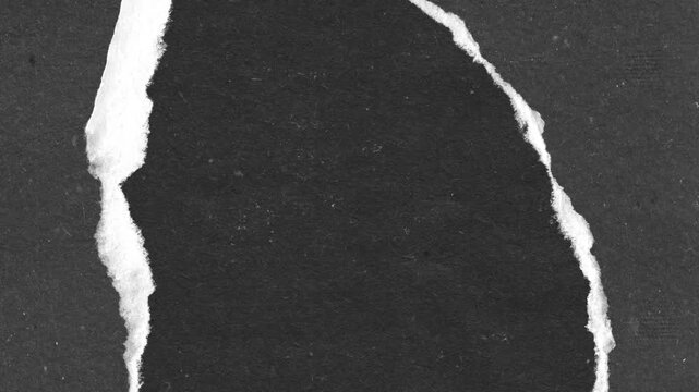 Abstract torn paper revealing black surface with white edges and textural details close up