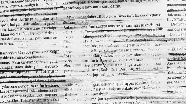 Close up of heavily marked and scribbled text on paper with black ink lines and smudges creating