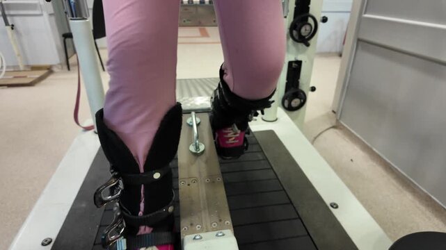 Legs of person in ski boots training on pro simulator at gym for physical therapy workout.