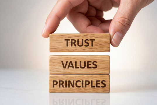 Human hand carefully stacking polished wooden blocks engraved with trust values and principles