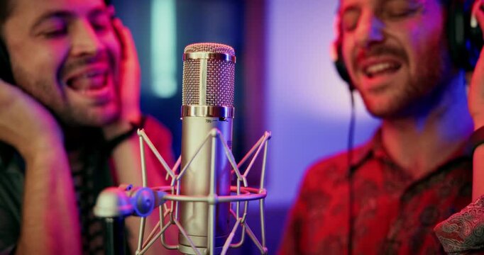 Microphone, men and singers in studio with headphones for recording music, song or album. Musicians, creative talent and people for production of audio track together in sound booth in collaboration