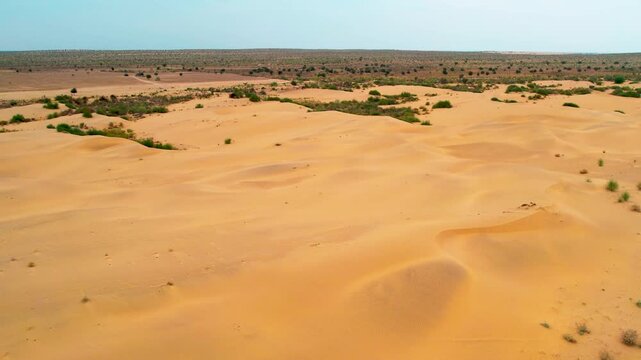 Tracking drone shot of golden sand dunes in Jaisalmer, Rajasthan. Captures the vast desert terrain and natural patterns of the Thar Desert from a smooth aerial perspective.
