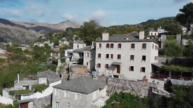 Stone houses with red shutters nestled in the scenic mountain village of Kalarrytes, Greece. Ideal for cultural and travel content.
