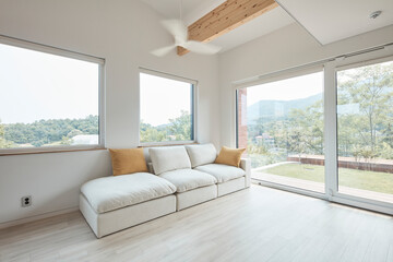 Fototapeta premium Bright living room with low sofa and broad windows in contemporary home