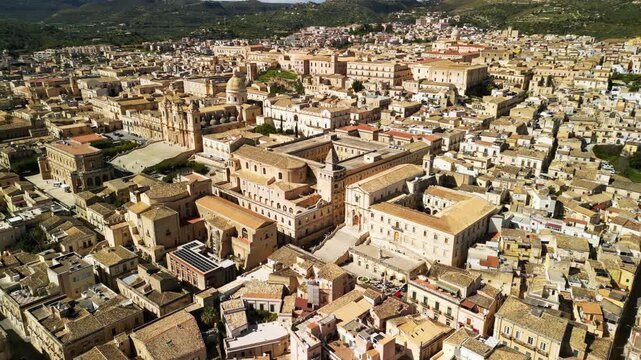 Aerial view of Noto, Sicily showcasing historic architecture, terracotta rooftops, and lush green hills in the background, capturing the essence of this beautiful Italian town. panorama