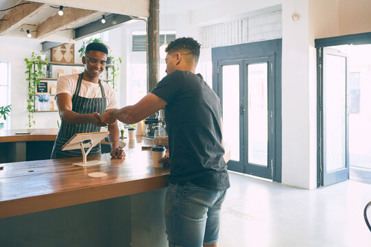 Coffee shop, man and business owner with smile for order, sale or customer service. Entrepreneur, waiter or barista with POS machine for payment, retail checkout and ecommerce technology in cafeteria