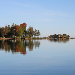 Obraz premium Colorful trees in Vita Sannar mirroring in Lake Vanern, autumn day in Sweden.