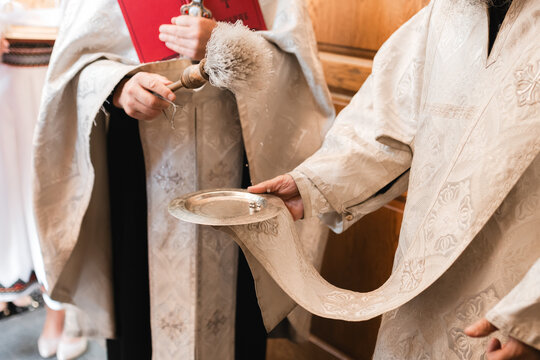 Priest blessing wedding rings with holy water during an Orthodox ceremony.