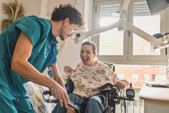 Healthcare worker helping smiling woman in electric wheelchair