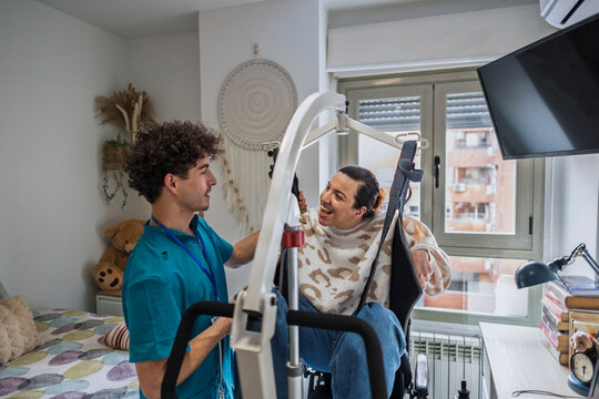 Caregiver assisting woman using mobility lift at home