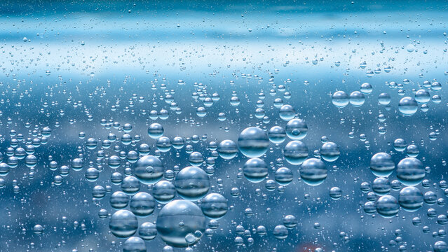 Oil and water droplets mixing in blue abstract liquid