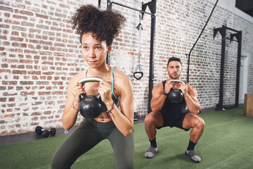 Fototapeta premium Woman, squat and man with kettlebell in gym, personal trainer or training together for body strength. Health club, people and workout routine with coach, fitness and balance for muscle development
