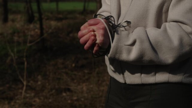 Horizontal shot of hands tied with cables against a forest background. A woman unties the wires and finds freedom. Digital detox concept.