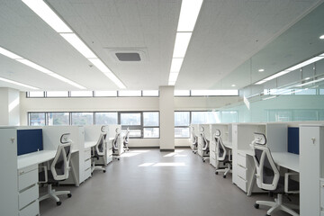 Fototapeta premium Contemporary workspace with white desks and broad window wall