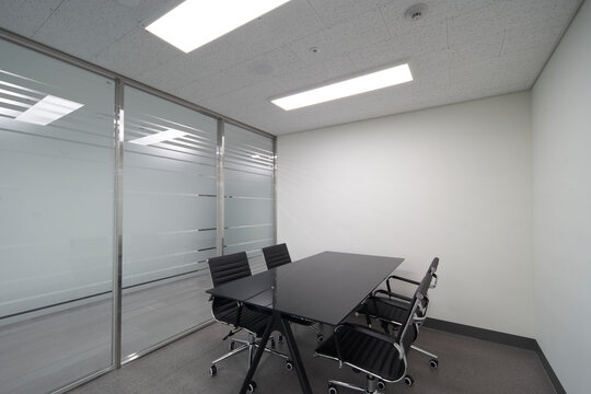 Small meeting room with black chairs and blinds in modern office