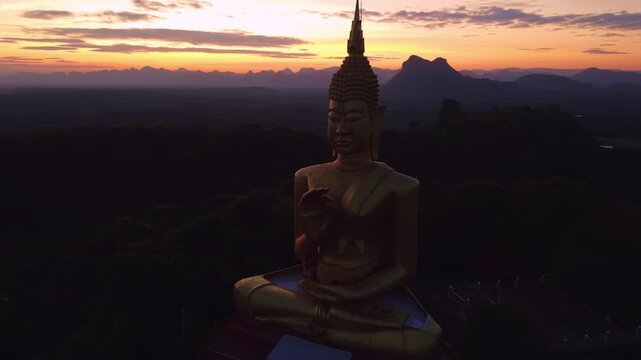 Buddhism monument Gold Big Buddha on Sunset in Thailand. Aerial top view Wat Khao Chedi Wisai Tri Rattanaram.