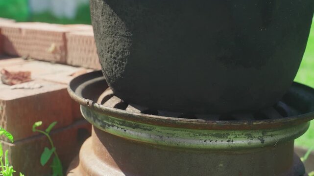Rusty Ring Supporting Potted Planter Weathered Clay Pot Sits Atop Metal Ring And Brick Base With Seedlings At Rim, Afternoon Sun Highlights Terracotta Texture And Patina In Cozy Urban Backyard Upcycle
