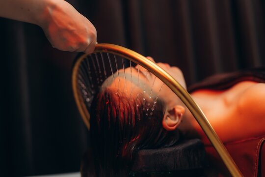 Woman experiencing relaxing hydrotherapy head treatment in spa. Japanese spa head