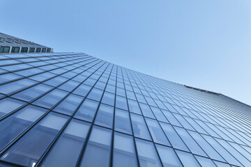 Fototapeta premium Low angle view up blue glass office tower against clear sky