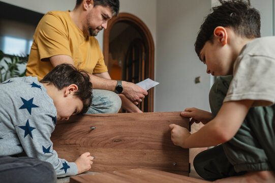 Father and children assembling furniture together at home