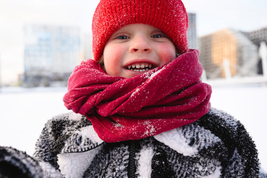 Smiling child outdoors in winter wearing red hat and scarf