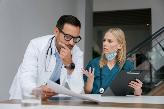 Doctor and nurse discussing patient medical care in hospital office