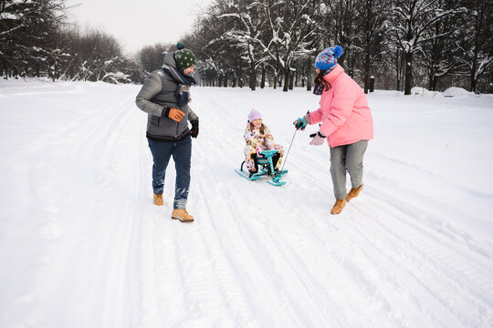 Family enjoying winter together outdoors with sled in the snow