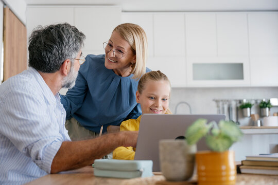 Grandparents and girl learning together at home using a laptop