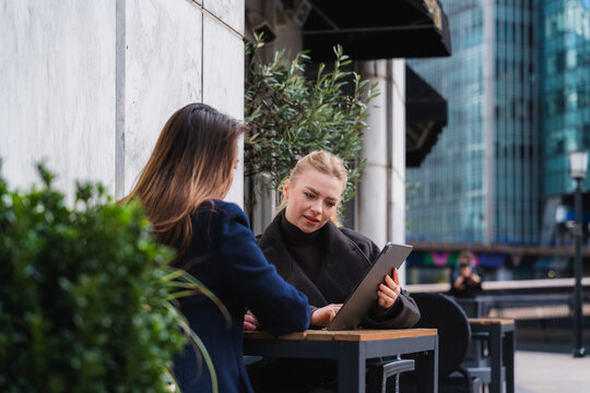 Colleagues discussing business using a tablet outdoors in urban setting