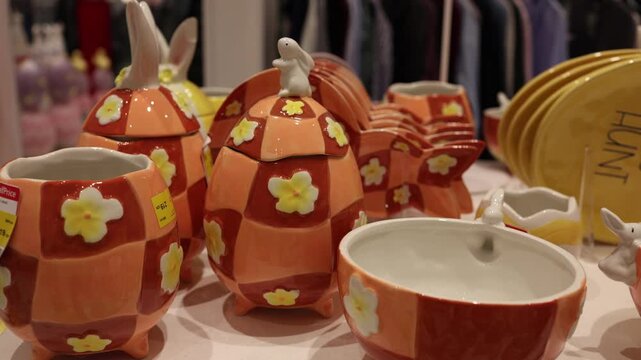 Easter colorful ceramic dishes shaped like eggs with bunny details and floral patterns arranged on store shelf creating festive spring kitchen decor and holiday shopping concept