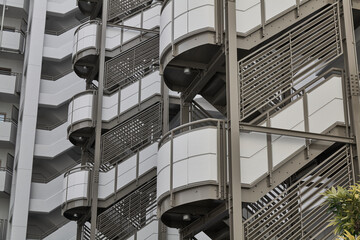 Dense apartment facade with round balconies and metal screens © Namsun