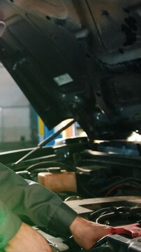 Mechanic in overalls checks level of engine oil in the car - automobile service repairing