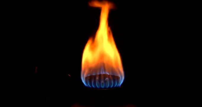 Closeup of a gas burner flame burning brightly in the dark.