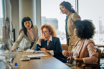 Obraz premium Diverse businesswomen collaborating discussing project in modern office