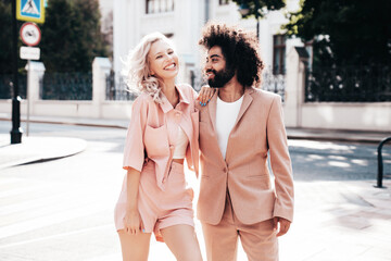 Beautiful fashion woman and her handsome elegant boyfriend in beige suit. Sexy blond model in summer suit clothes. Fashionable smiling couple posing in street Europe. Brutal man and female outdoors © halayalex