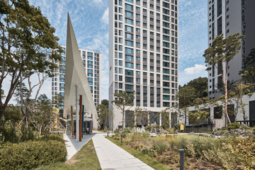 Apartment garden path with sculptural monument and tall residential towers © Namsun