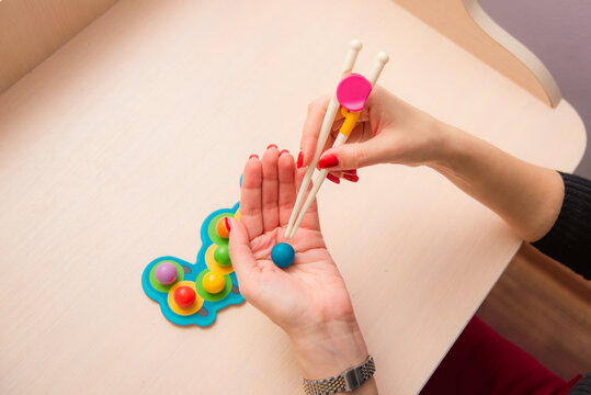 woman learning child motor skill game with sticks and ball, close up woman hands