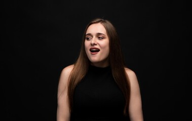 Naklejka premium Young woman looking away with open mouth expressing curiosity, surprise or disgust on a black background
