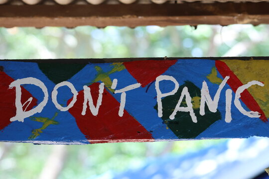 Panneau &ldquo;Don&rsquo;t panic&rdquo; sur fond color&eacute;, message humoristique et positif