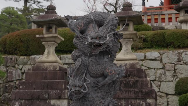 Detailed stone dragon statue at Kiyomizu-dera Temple, stone lanterns and red shrine building behind
