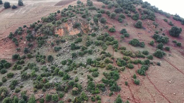 Detailed 4K drone shot of severe vertical soil erosion and water runoff tracks on a rugged mountain slope in Morocco's Middle Atlas region.